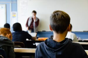 Teacher sneezing in front of students in a classroom with indoor air disinfection from Farlite.