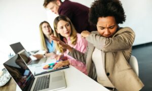 coworker sneezing and spreading germs in space needing indoor air disinfection